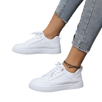 White casual lace-up sneakers on feet wearing cropped blue jeans and a beaded ankle bracelet
