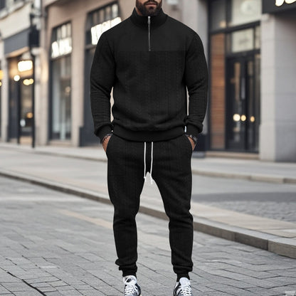 Man wearing black cable-knit half-zip sweater and matching jogger pants with white drawstring on city street