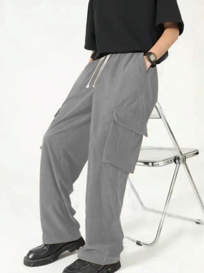 Person wearing loose gray cargo pants with pockets and black shoes sitting on metal folding chair