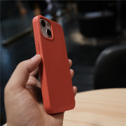 Hand holding a smartphone with a red protective case in a dim indoor setting