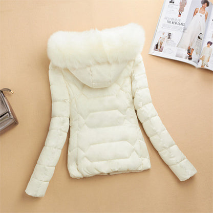 White quilted winter jacket with fluffy hood on beige background, fashion magazine and purse beside
