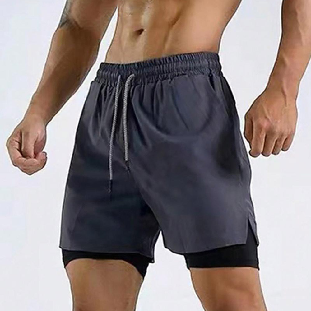 Athletic man wearing black double-layered workout shorts with drawstring waist