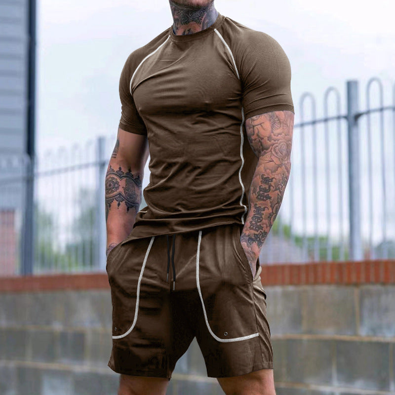 Muscular man with tattoos wearing brown athletic t-shirt and shorts with white piping outdoors