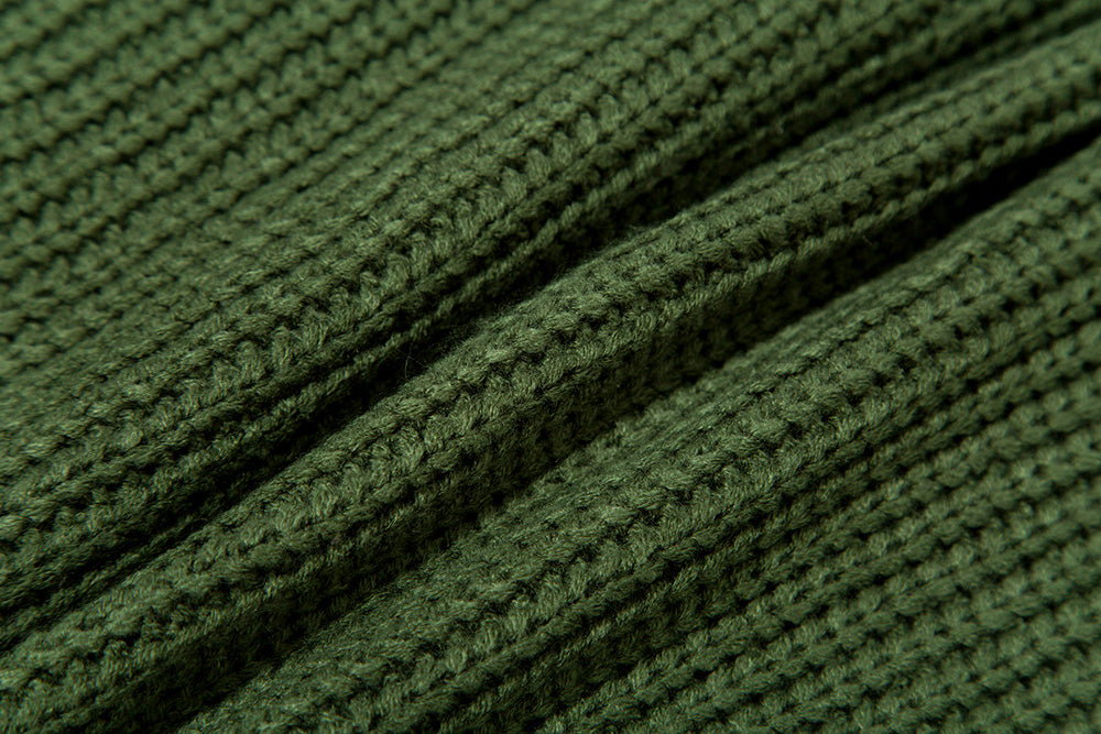 Close-up of green knitted fabric with ribbed texture and soft wool fibers