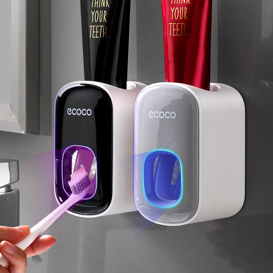 Ecoco wall-mounted automatic toothpaste dispensers in black and white with toothbrush and toothpaste tubes