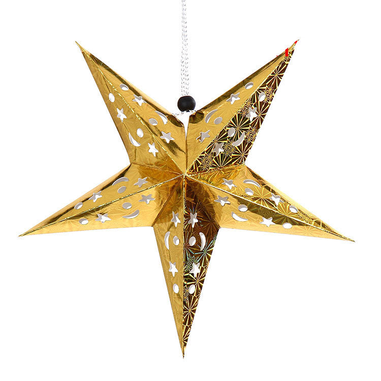 Gold paper star lantern with moon and star cutouts hanging by silver string