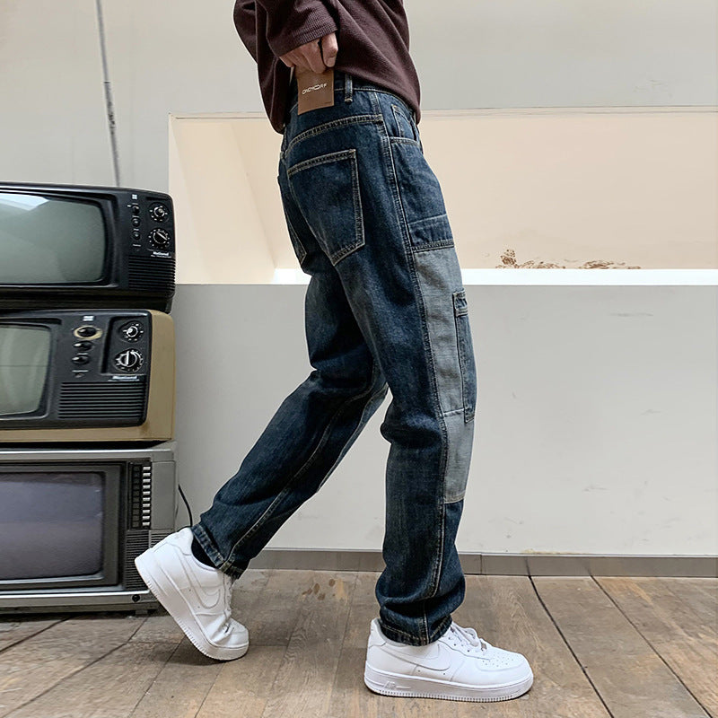 Person wearing dark patchwork denim jeans and white Nike sneakers standing indoors with vintage TVs