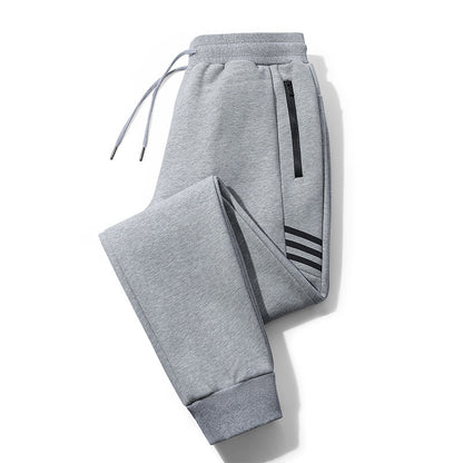 Gray sweatpants with elastic cuffs, drawstring waistband, black zipper pocket, and three black stripes detail