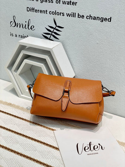 Orange leather handbag on white textured surface with layered hexagonal frames and wall text