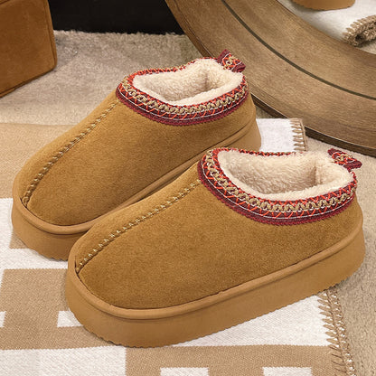 Cozy brown slip-on slippers with fleece lining and decorative red and gold trim on beige carpet