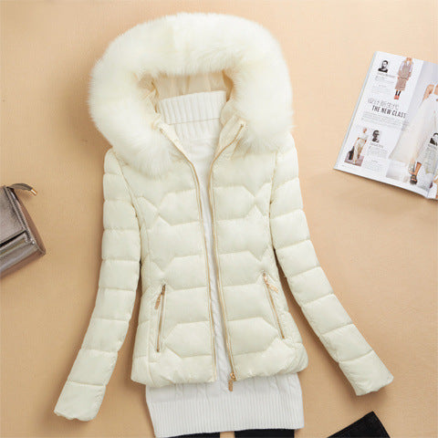 cream white puffer jacket with fur hood and zipper pockets laid flat on beige background