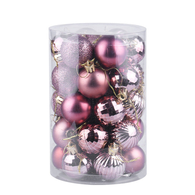 Clear plastic cylinder filled with assorted pink Christmas tree ornaments in shiny, matte, glitter, and ribbed finishes