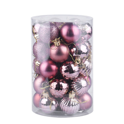 Clear plastic cylinder filled with assorted pink Christmas tree ornaments in shiny, matte, glitter, and ribbed finishes