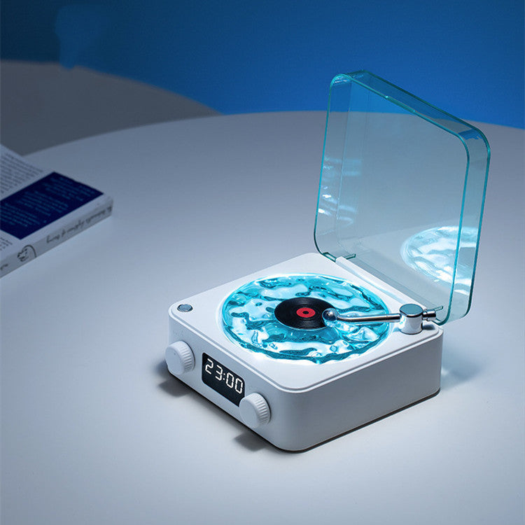 Compact white digital clock with a blue liquid record design and transparent lid on a white table