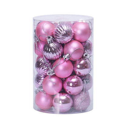 Clear cylindrical container filled with assorted pink Christmas ornaments including matte, shiny, ribbed, and glitter finishes