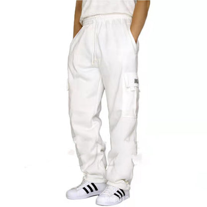 Person wearing white cargo jogger pants with pockets and white Adidas sneakers with black stripes