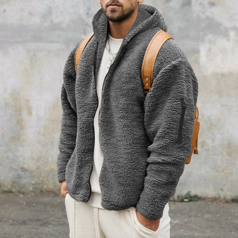Man wearing gray fleece zip-up jacket with hood and brown leather backpack outdoors