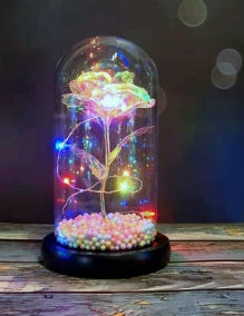 LED fairy lights wrapped around a glowing rose inside a glass dome with colorful beads at the base