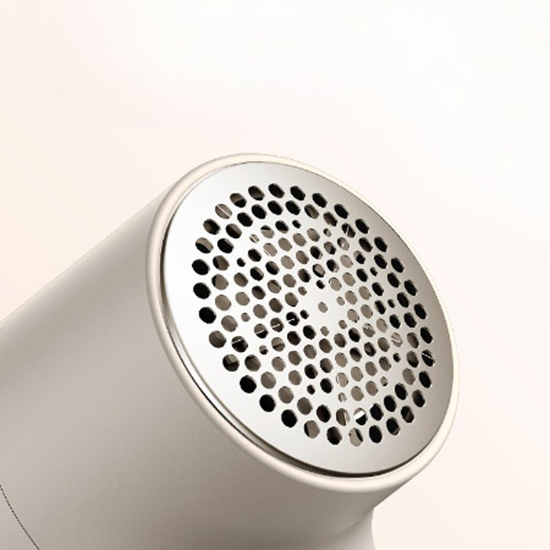Close-up of cream fabric shaver with circular perforated metal blade guard against soft background