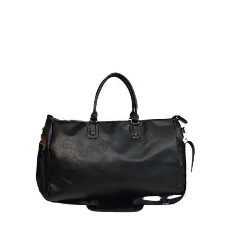 Black leather duffel bag with double handles and detachable shoulder strap on white background