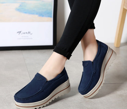 Woman wearing navy blue slip-on platform loafers with black pants indoors