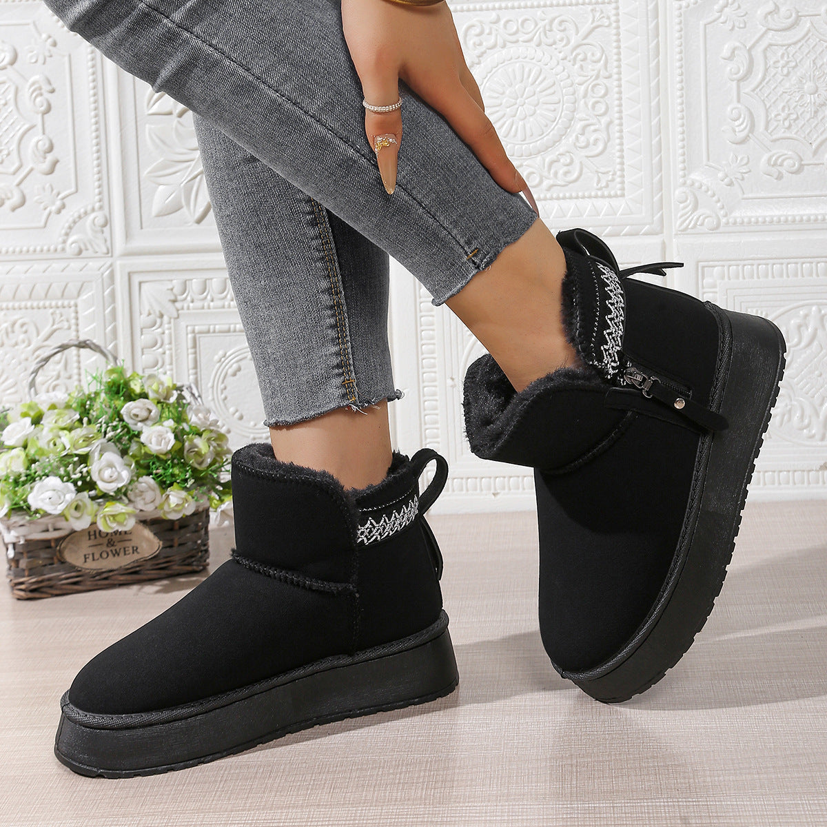 Woman wearing black winter fur-lined ankle boots with chunky soles and decorative stitching