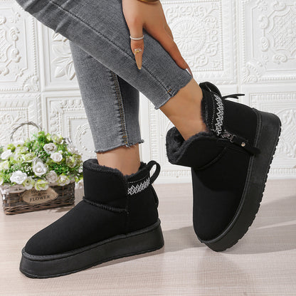 Woman wearing black winter fur-lined ankle boots with chunky soles and decorative stitching