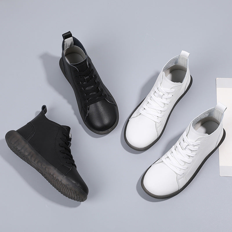 Pair of black and pair of white high-top leather sneakers with black soles on light gray background