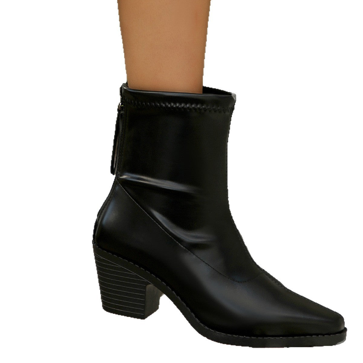 Black leather ankle boot with block heel and side zipper on model's foot