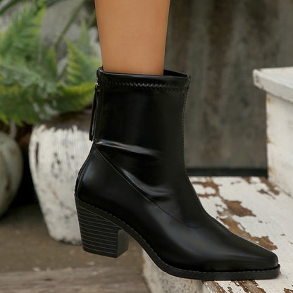 Black leather ankle boot with block heel worn on foot, outdoors on rustic white wooden steps