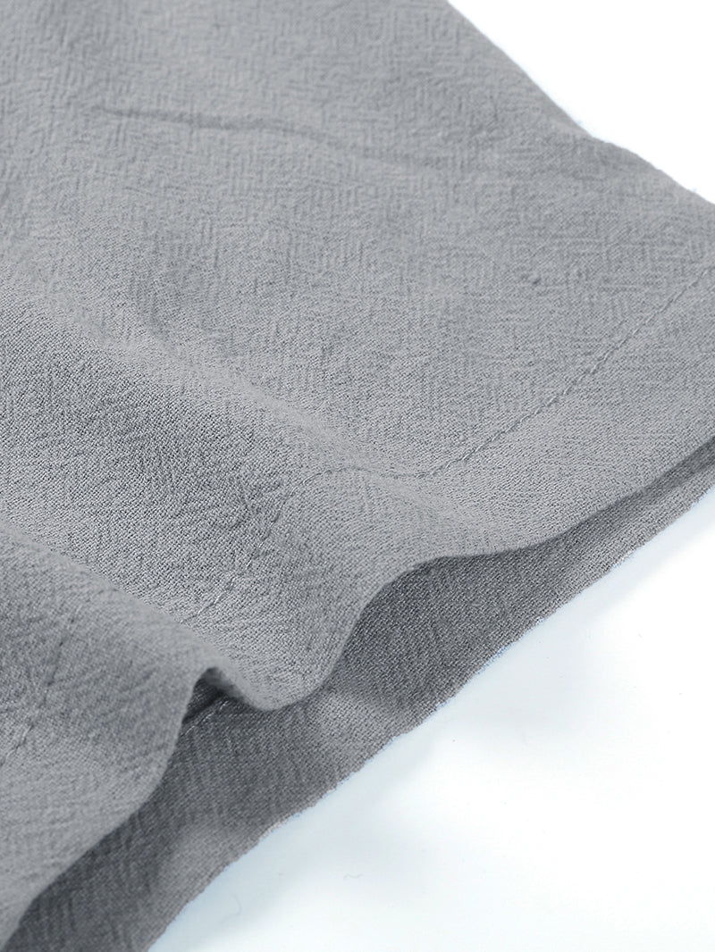Close-up of gray textured fabric with stitched hem on a white background