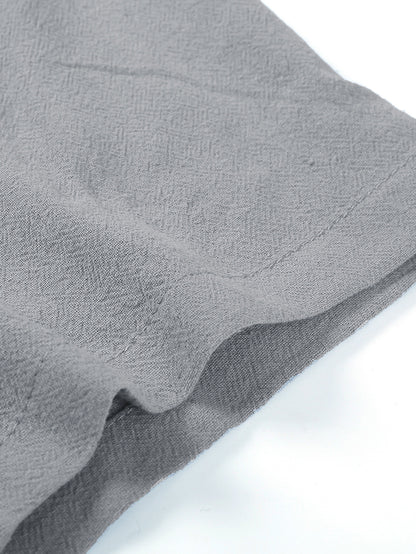 Close-up of gray textured fabric with stitched hem on a white background