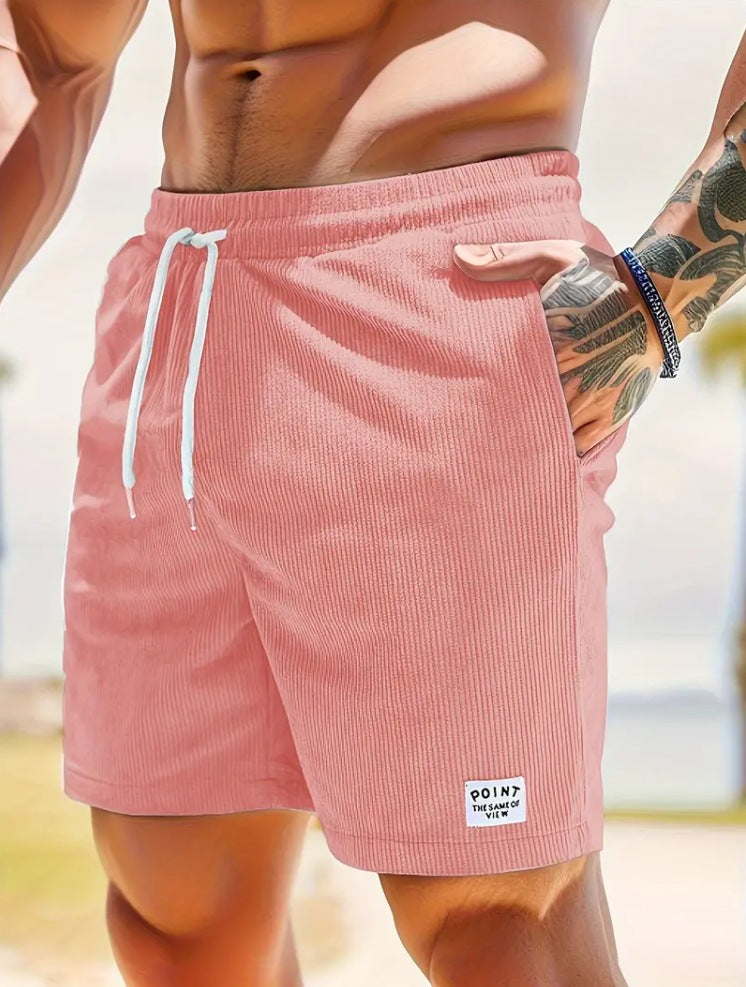 Close-up of muscular man wearing pink corduroy shorts with white drawstring and tattooed arm