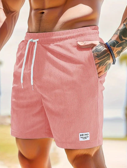 Close-up of muscular man wearing pink corduroy shorts with white drawstring and tattooed arm