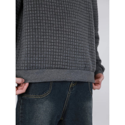 Close-up of person wearing textured gray sweatshirt and dark blue jeans with yellow stitching