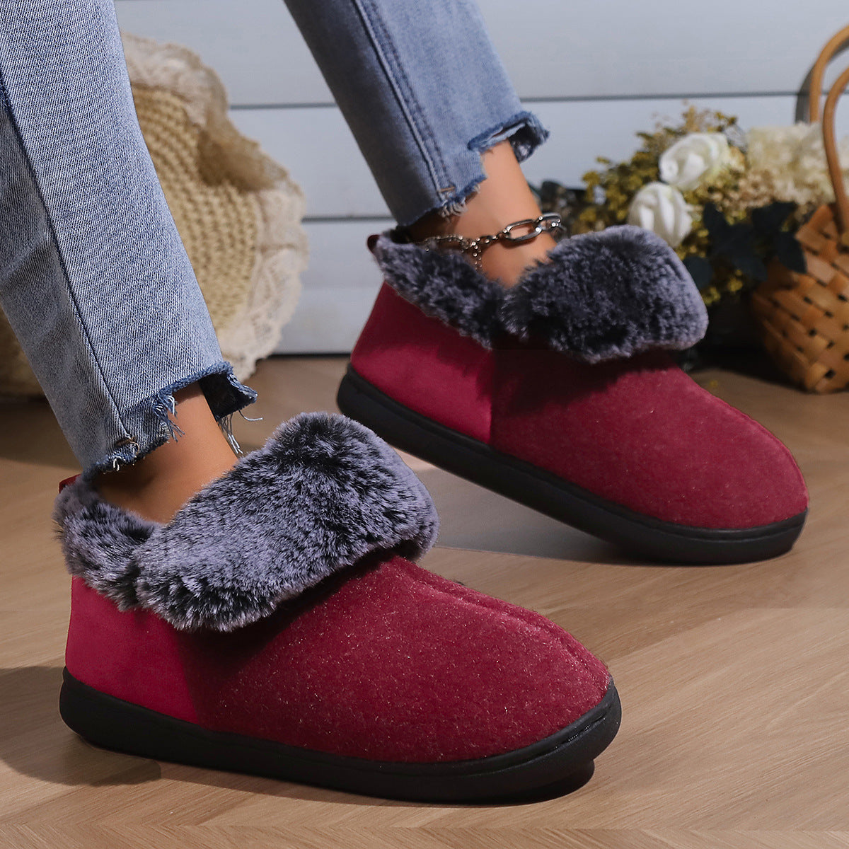 Woman wearing cozy red winter slippers with gray faux fur lining and black soles indoors