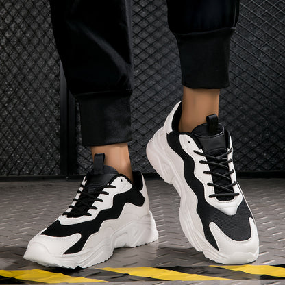 Black and white chunky sneakers with wave design worn with black pants on industrial floor