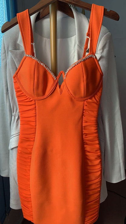 Bright orange ruched bodycon dress with rhinestone-trimmed bust, displayed on hanger over white blazer