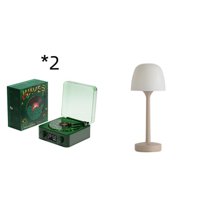 Two green Waves record players with clear lids and album covers, beside a beige table lamp with white shade