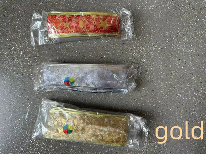 Three decorative ribbon trims in red, silver, and gold packaging on a speckled gray surface