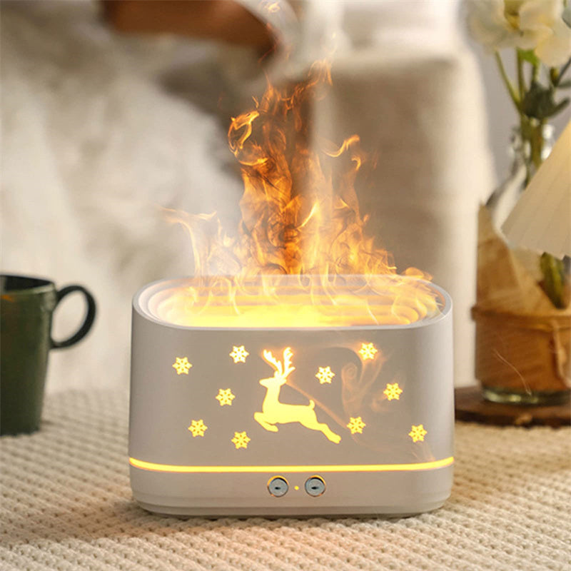 White essential oil diffuser with glowing reindeer and snowflake design emitting mist on a knitted surface