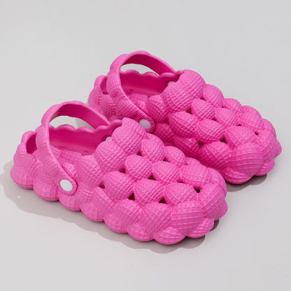 Pair of bright pink textured foam clogs with bubble-like surface and adjustable heel straps