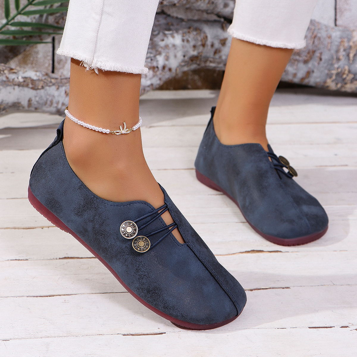 Woman wearing navy blue casual slip-on shoes with decorative buttons and white frayed jeans