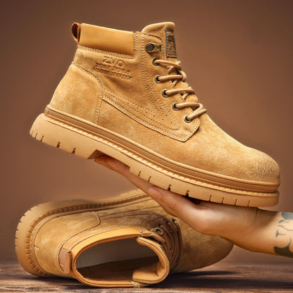 Tan suede fashion sports boots with rugged soles held by tattooed hand on brown background