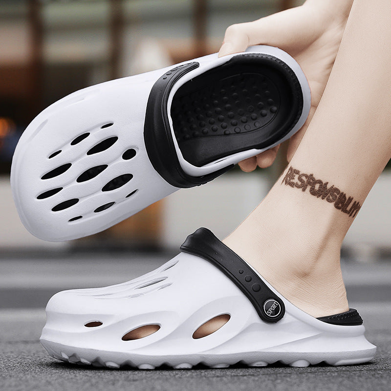 White slip-on clogs with black adjustable straps and ventilation holes worn on feet on a pavement
