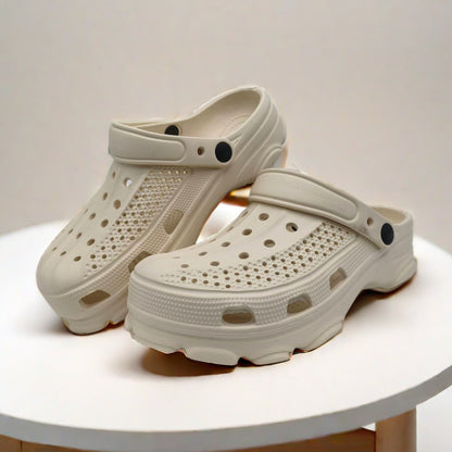 Pair of white ventilation hole clog shoes with adjustable heel straps on round white table