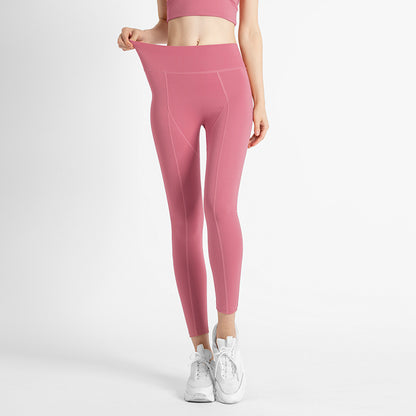 Woman wearing high-waisted pink leggings and white sneakers against white background