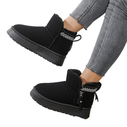 Black winter ankle boots with fur lining and patterned trim worn with grey jeans