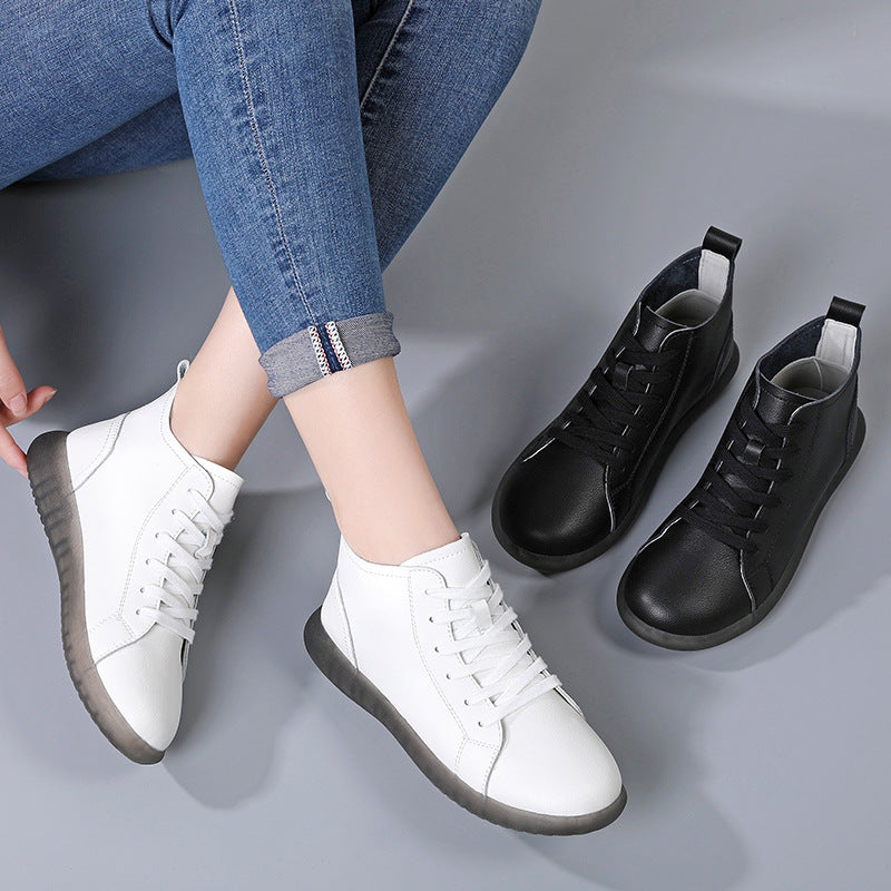 White and black casual lace-up ankle sneakers on gray background with person wearing white pair and jeans