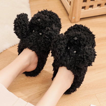 Black fluffy dog-shaped slippers worn on feet on wooden floor in cozy indoor setting